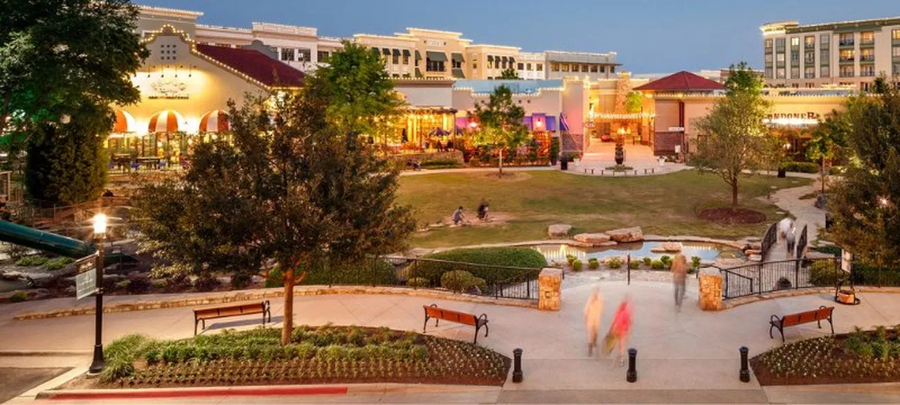 Evening view of the Watters Creek shopping and dining district in Allen, Texas, with string lights and a pond