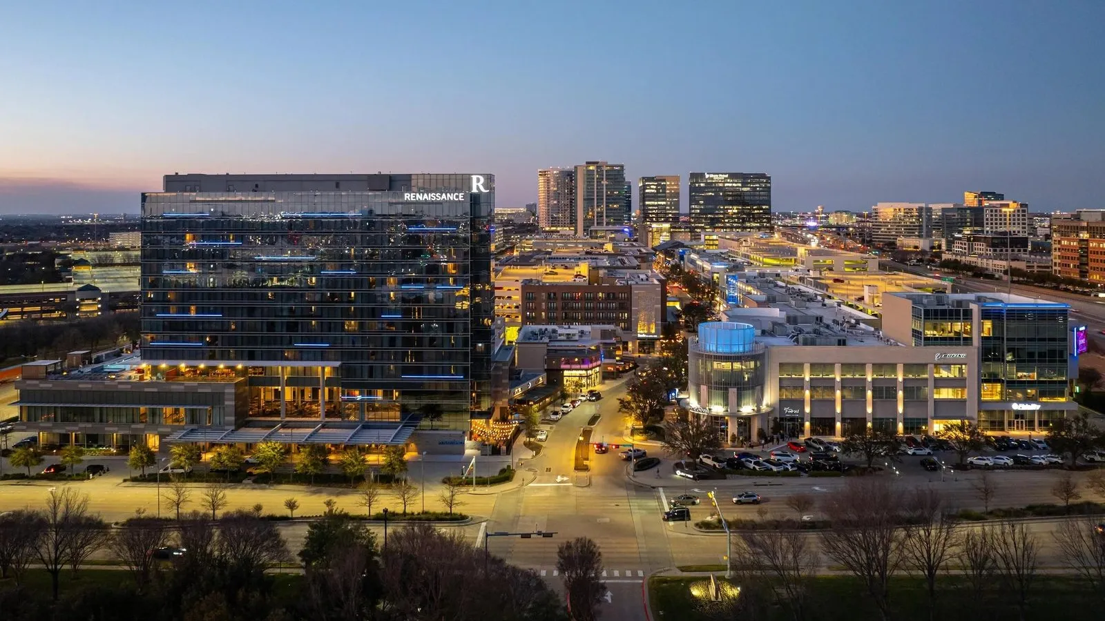 Aerial dusk view of the Legacy West district in Plano, Texas, with the Renaissance hotel and lit-up mixed-use towers
